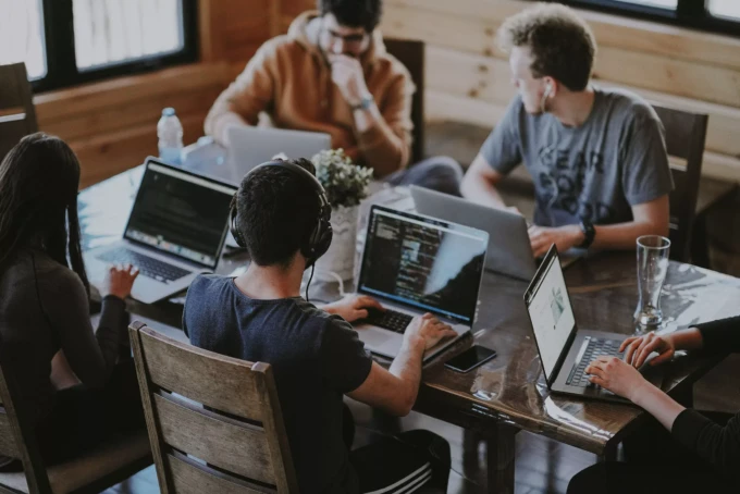 Six people working on their laptops together around a table