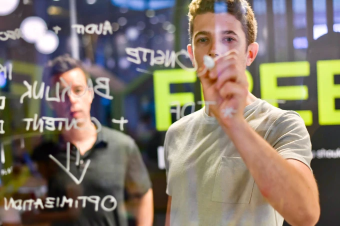 Photo of two men writing on a glass wall