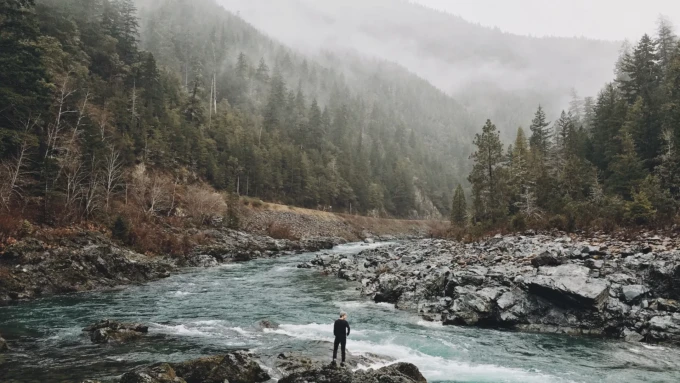 Person standin on rock beside a river running