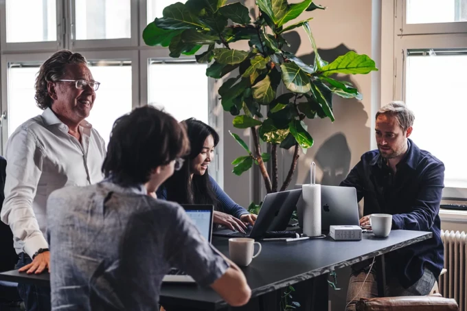 Photo of co-workers from the Swedish Besedo office standing and sitting around a desk.