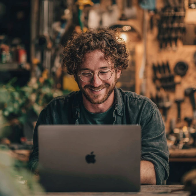 photograph of a man in his 30s deeply engaged in a happy reading on his MacBook.
